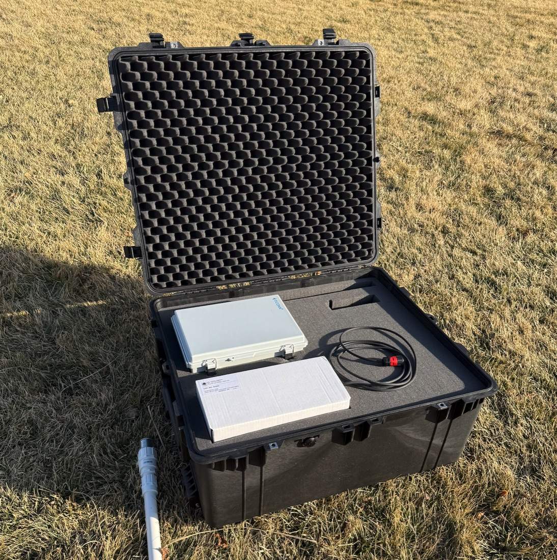Open Pelican case on grass with fitted foam holding the weather station's instruments and cabling